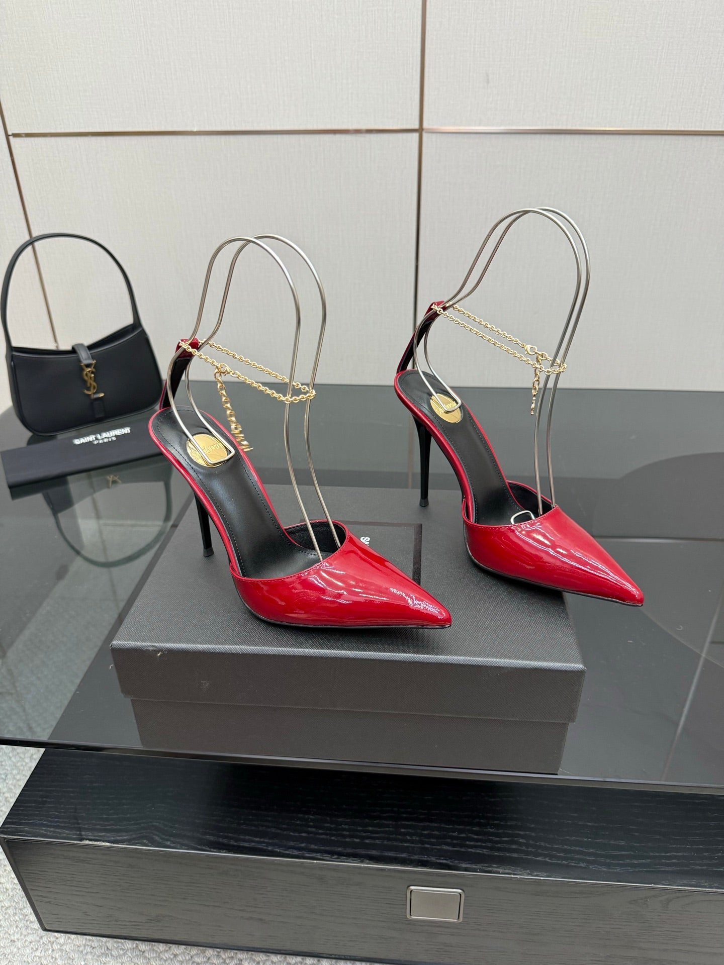 Pair of women’s red patent pointed-toe stiletto heels with gold chain slingbacks
