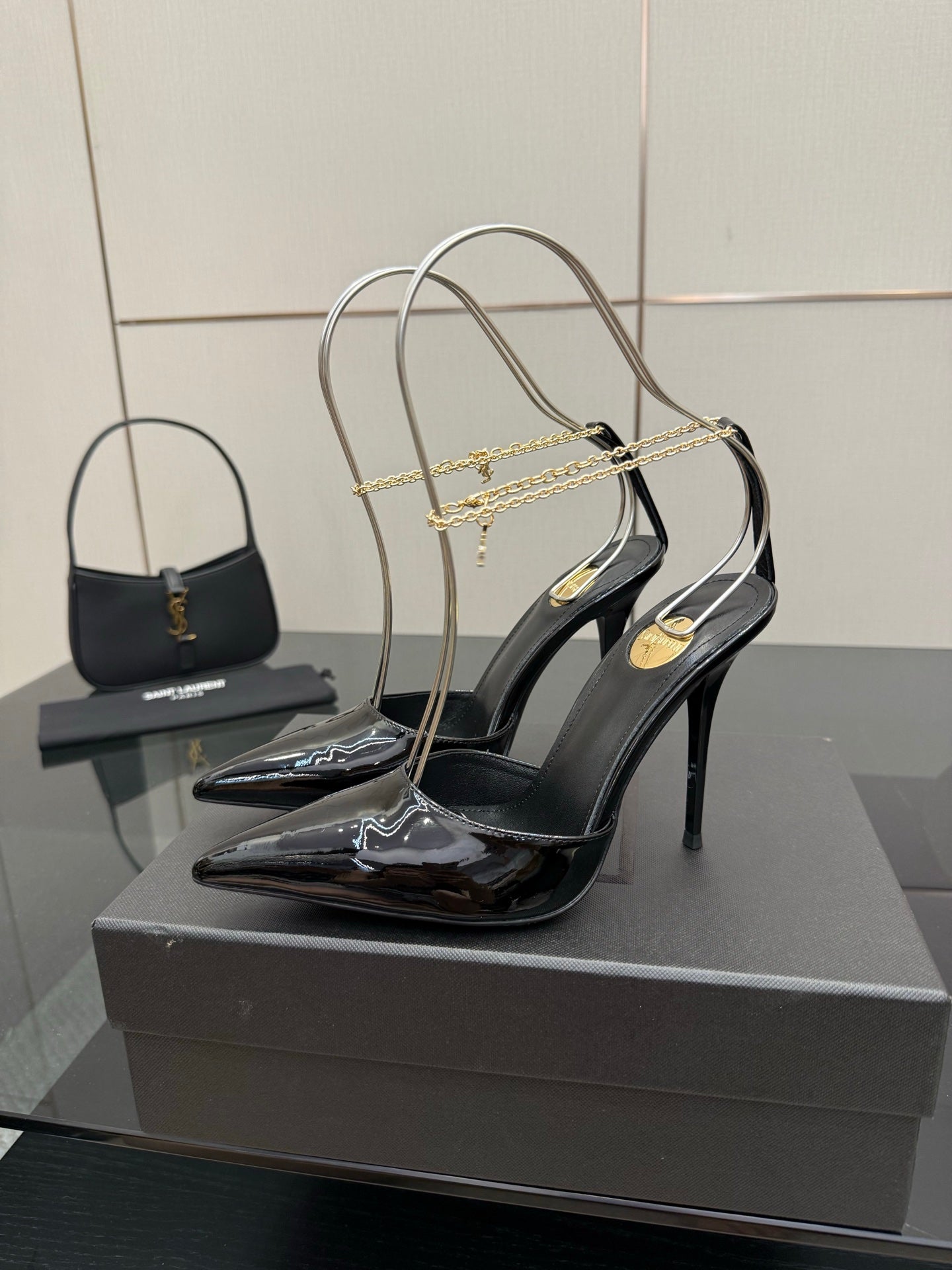 Women’s black patent leather high-heel slingback pumps with gold chain detailing