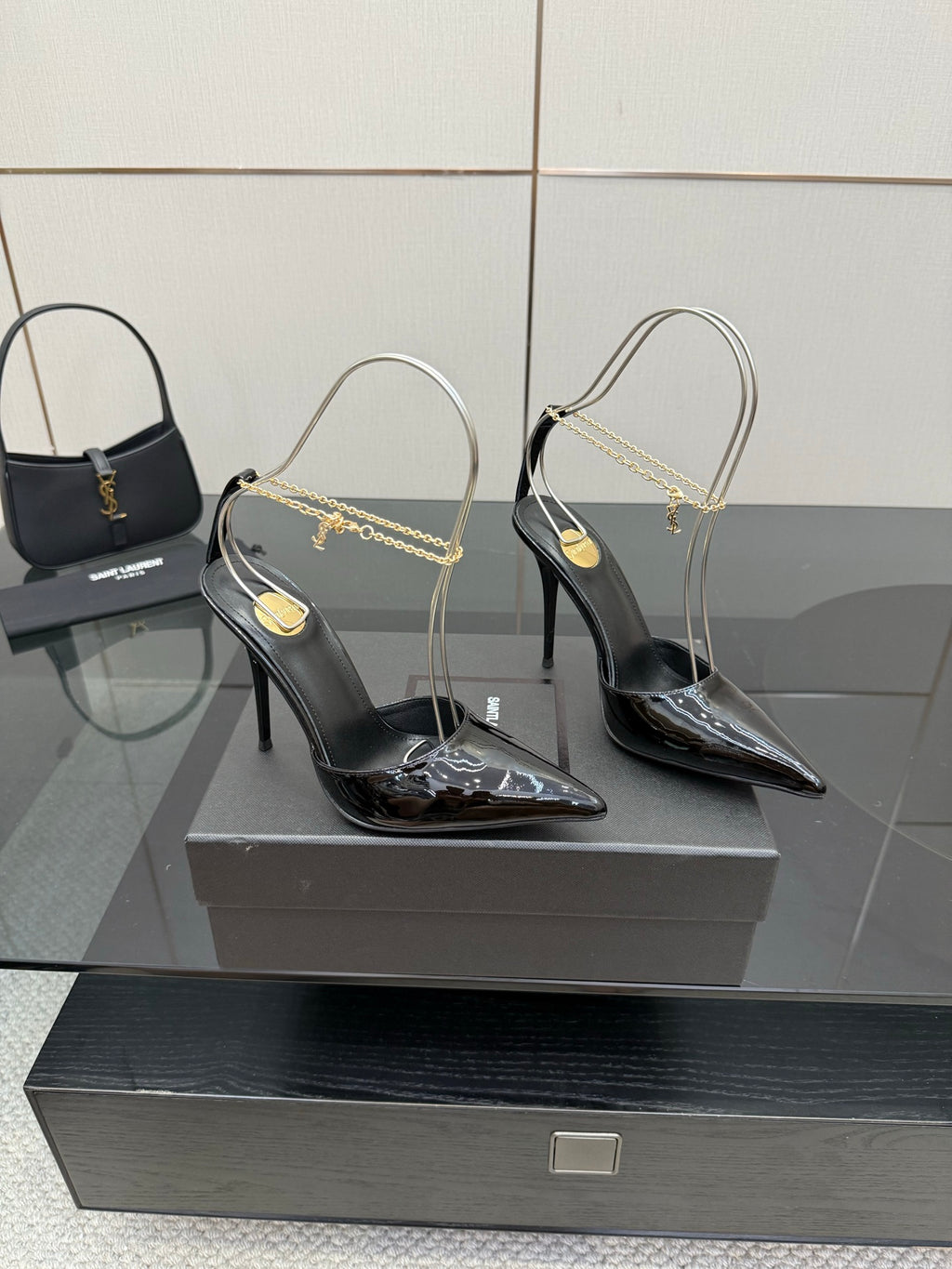 Women’s black patent leather pointed-toe high heels with gold chain strap