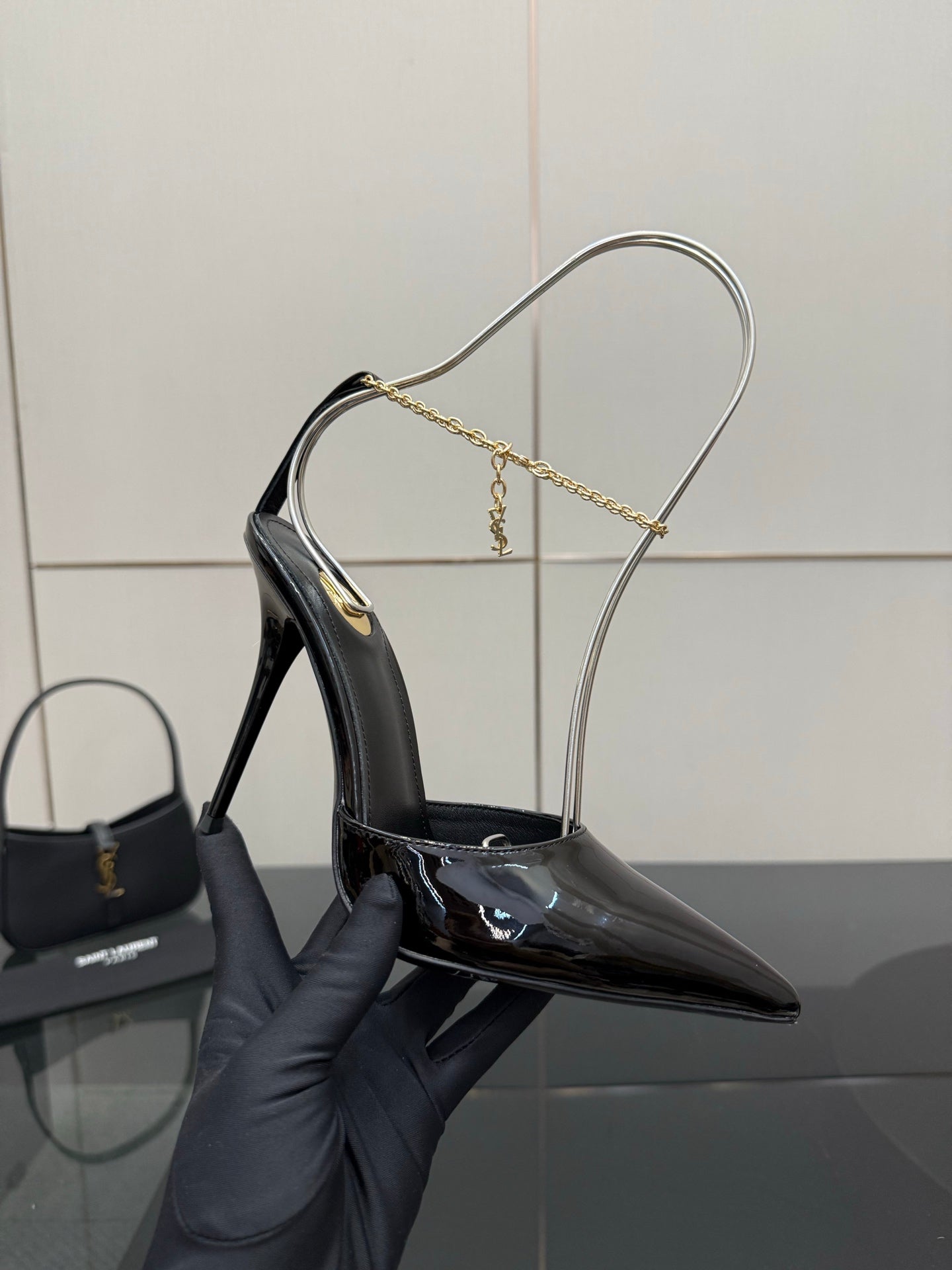Women’s black patent leather stiletto pump on gold chain slingback strap