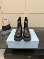 Black patent Chelsea boots with side Prada logo and chunky lug sole, pair on box