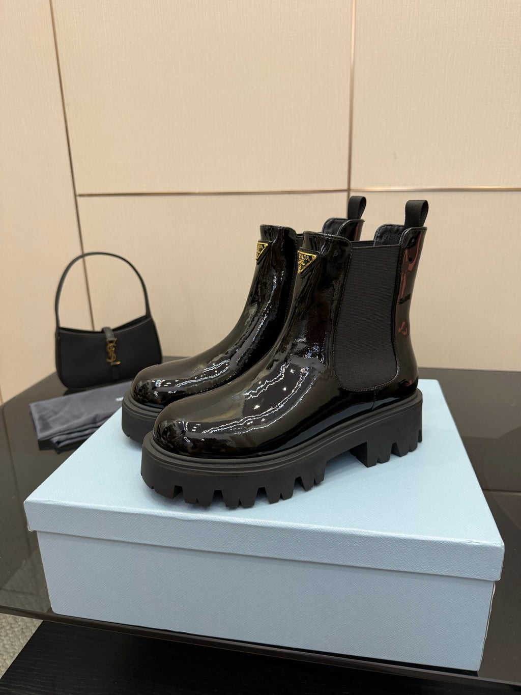 Black patent Chelsea boots with pull tabs and Prada logo badge, chunky tread sole