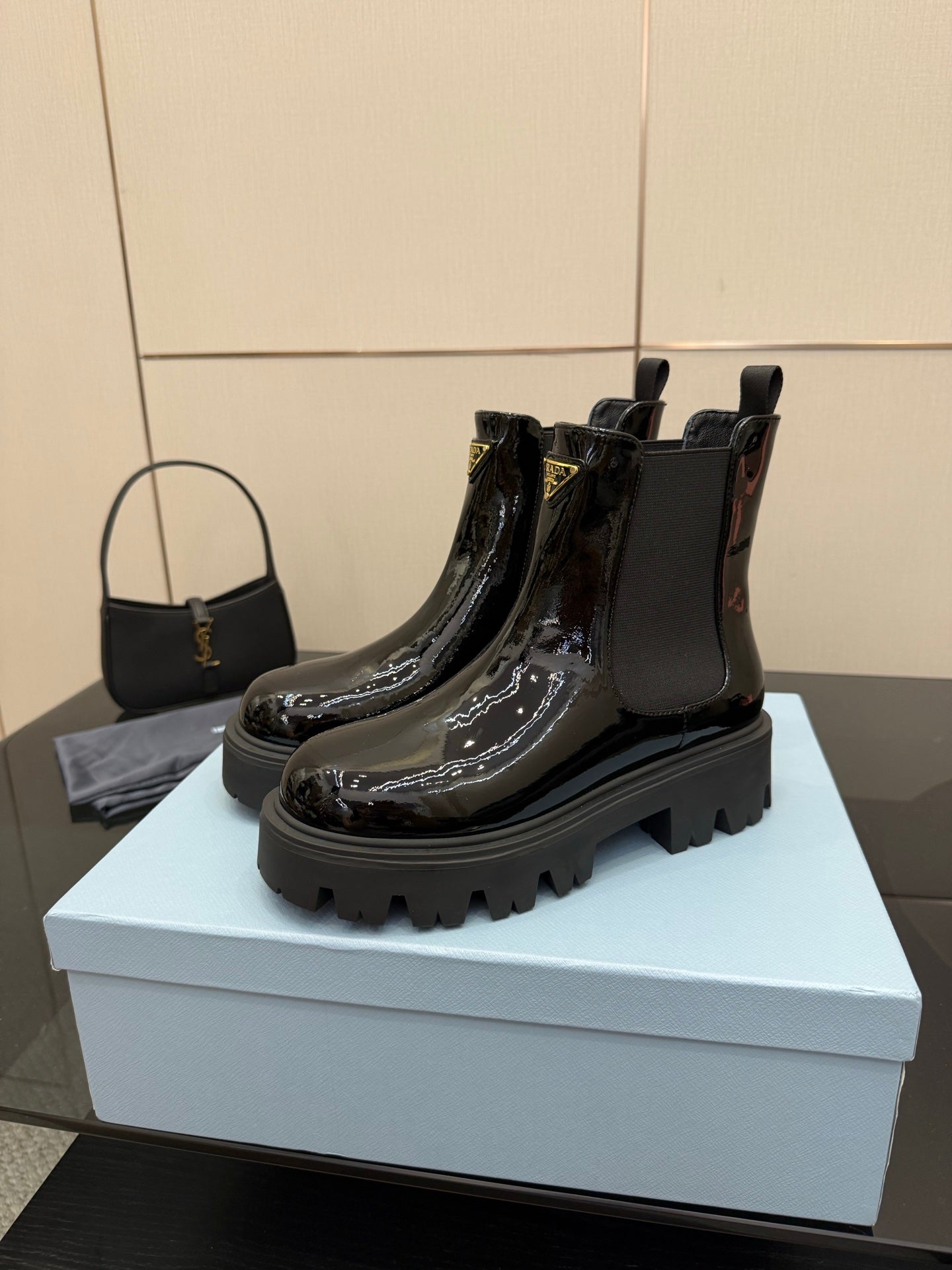 Black patent Chelsea boots with pull tabs and Prada logo badge, chunky tread sole