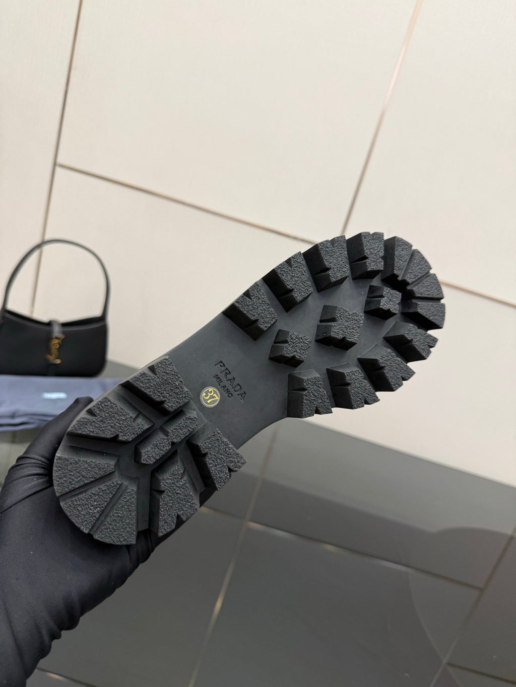 Black lug sole of Chelsea boot with tread pattern and Prada logo on outsole