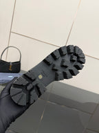 Black lug sole of Chelsea boot with tread pattern and Prada logo on outsole