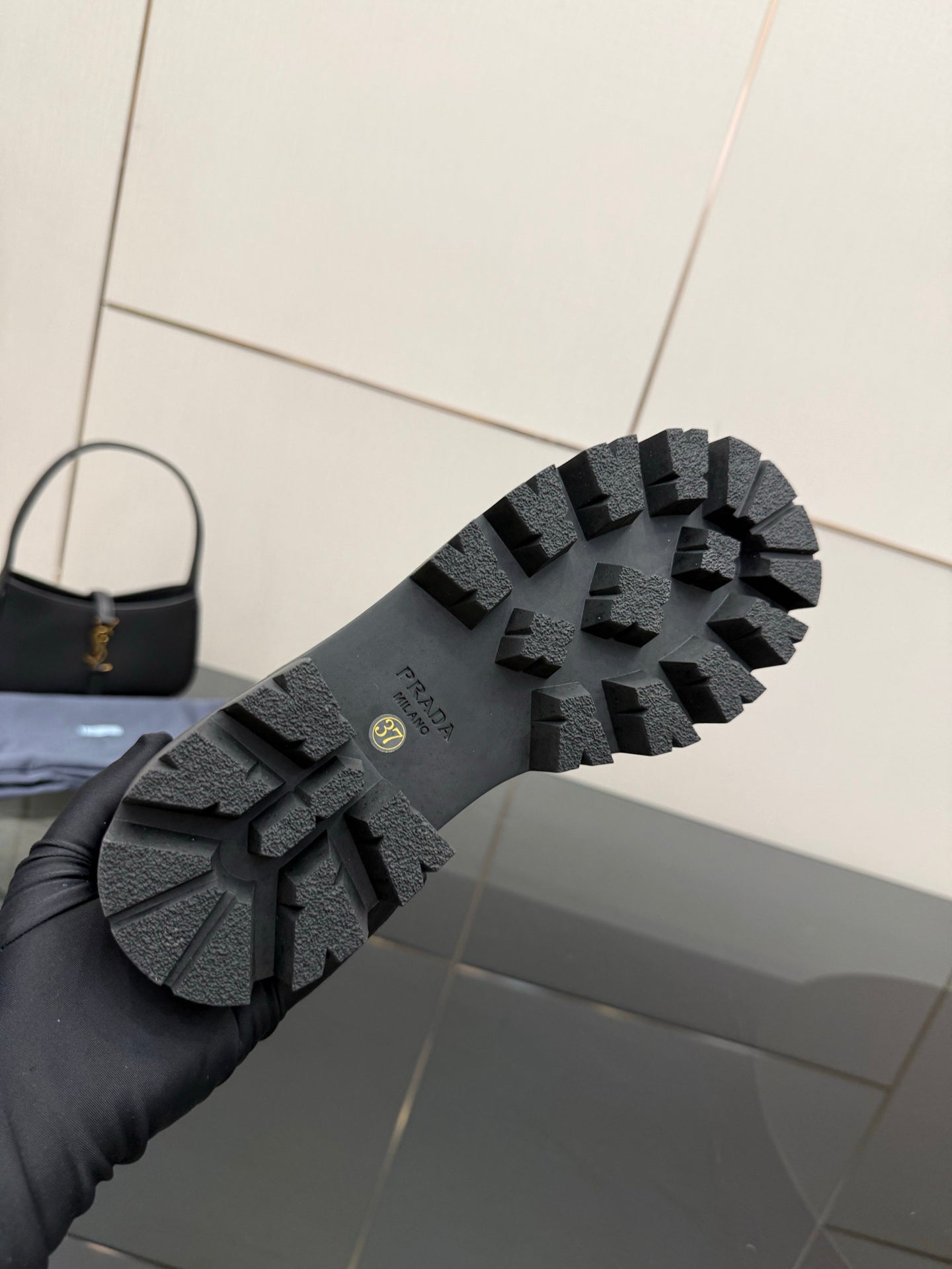 Black lug sole of Chelsea boot with tread pattern and Prada logo on outsole
