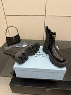 Black patent Chelsea boot with Prada side logo, shown with boot accessories on box