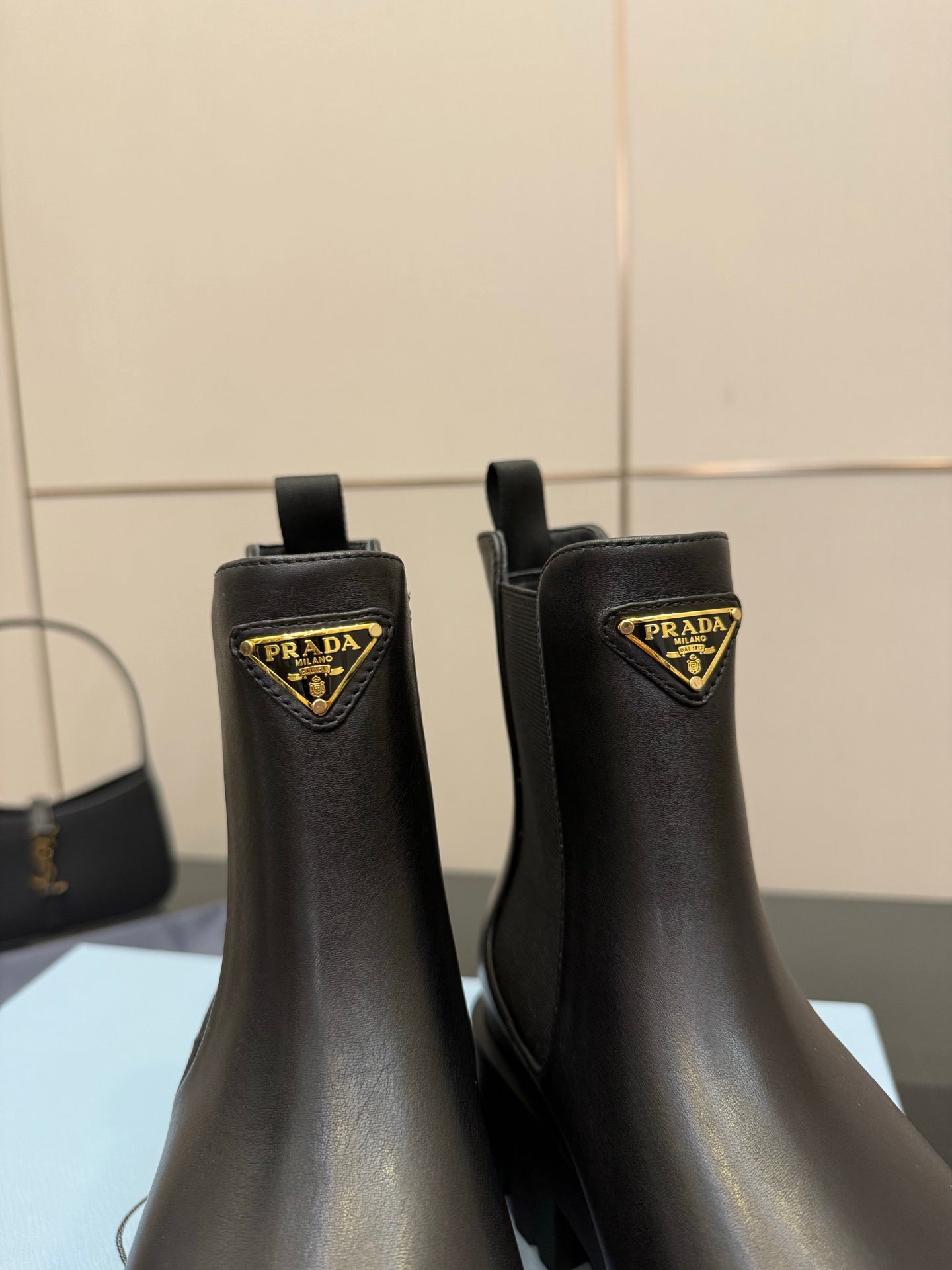Prada black leather Chelsea boots with gold logo triangle patch and pull-tab