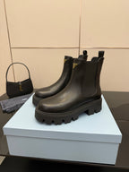 Prada black Chelsea ankle boot with gold logo patch and thick tread sole