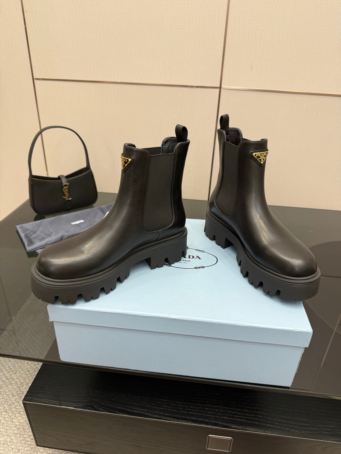 Prada black leather Chelsea boots with chunky lug sole and gold-trim logo patch