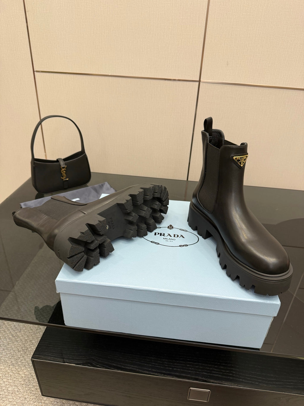 Prada black Chelsea boots with gold logo patch and raised lug tread sole