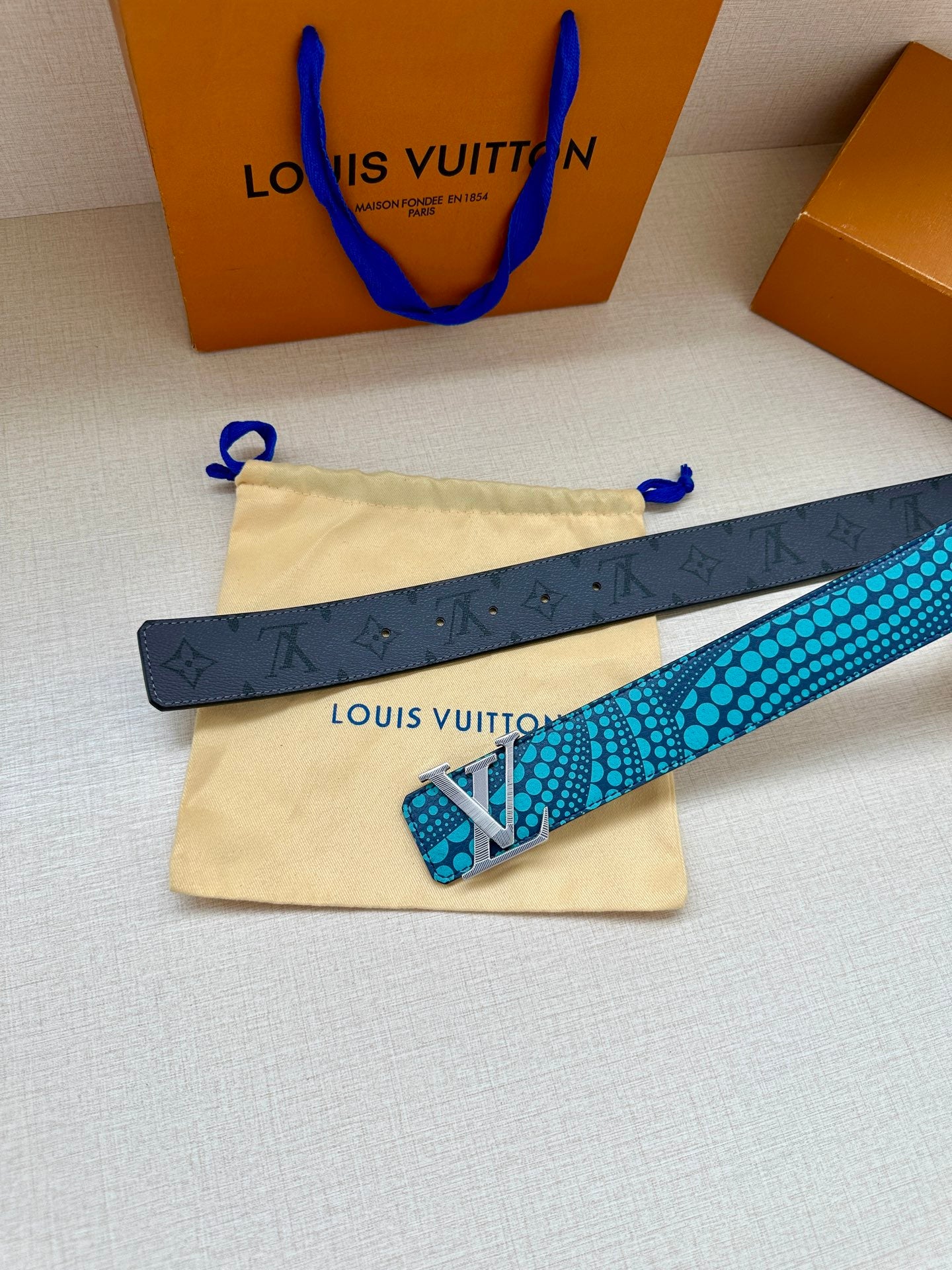 Louis Vuitton belt with turquoise dotted strap and silver LV buckle, flat lay