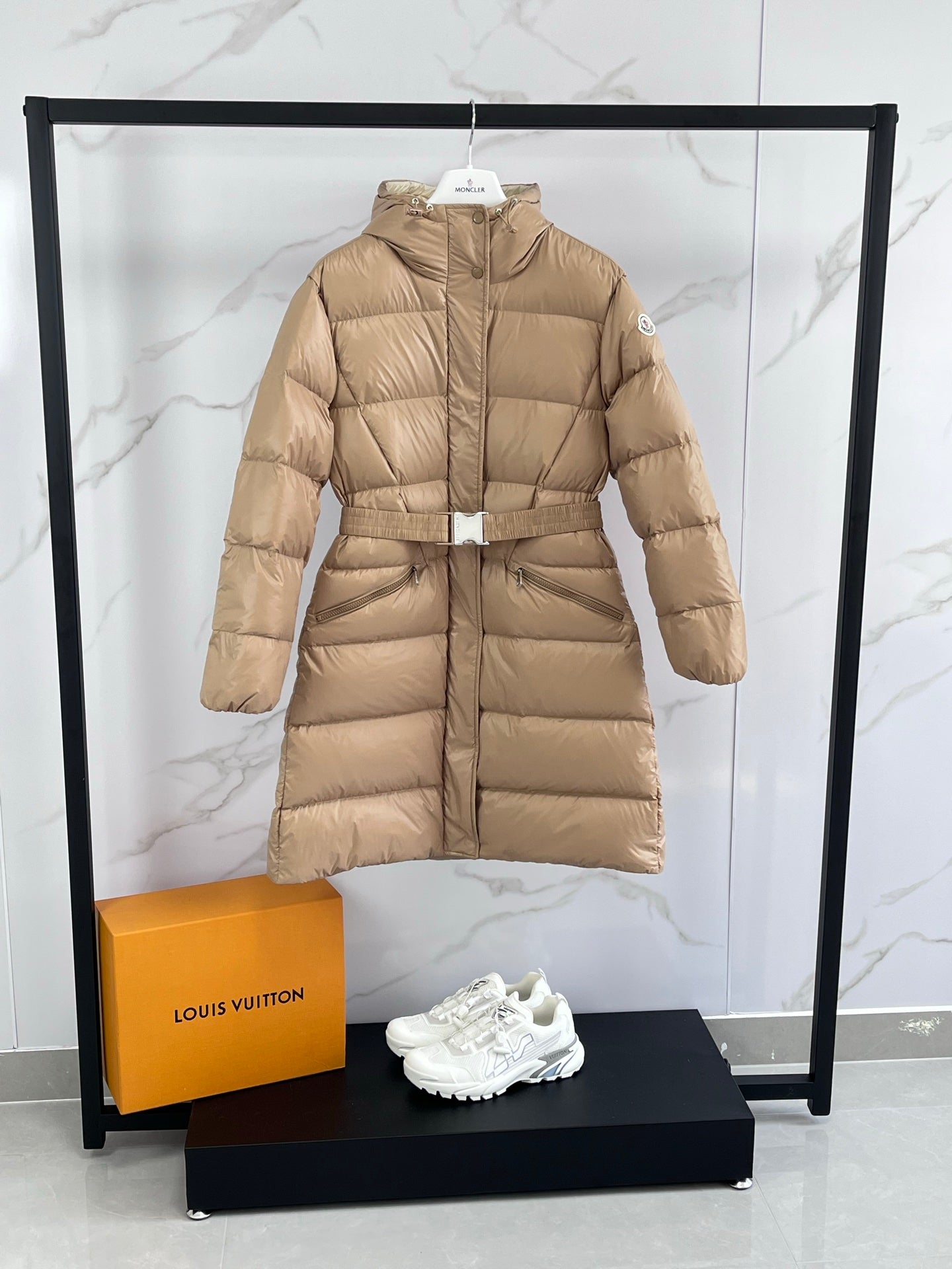 Tan long puffer coat with hood, front zip, and detachable belt