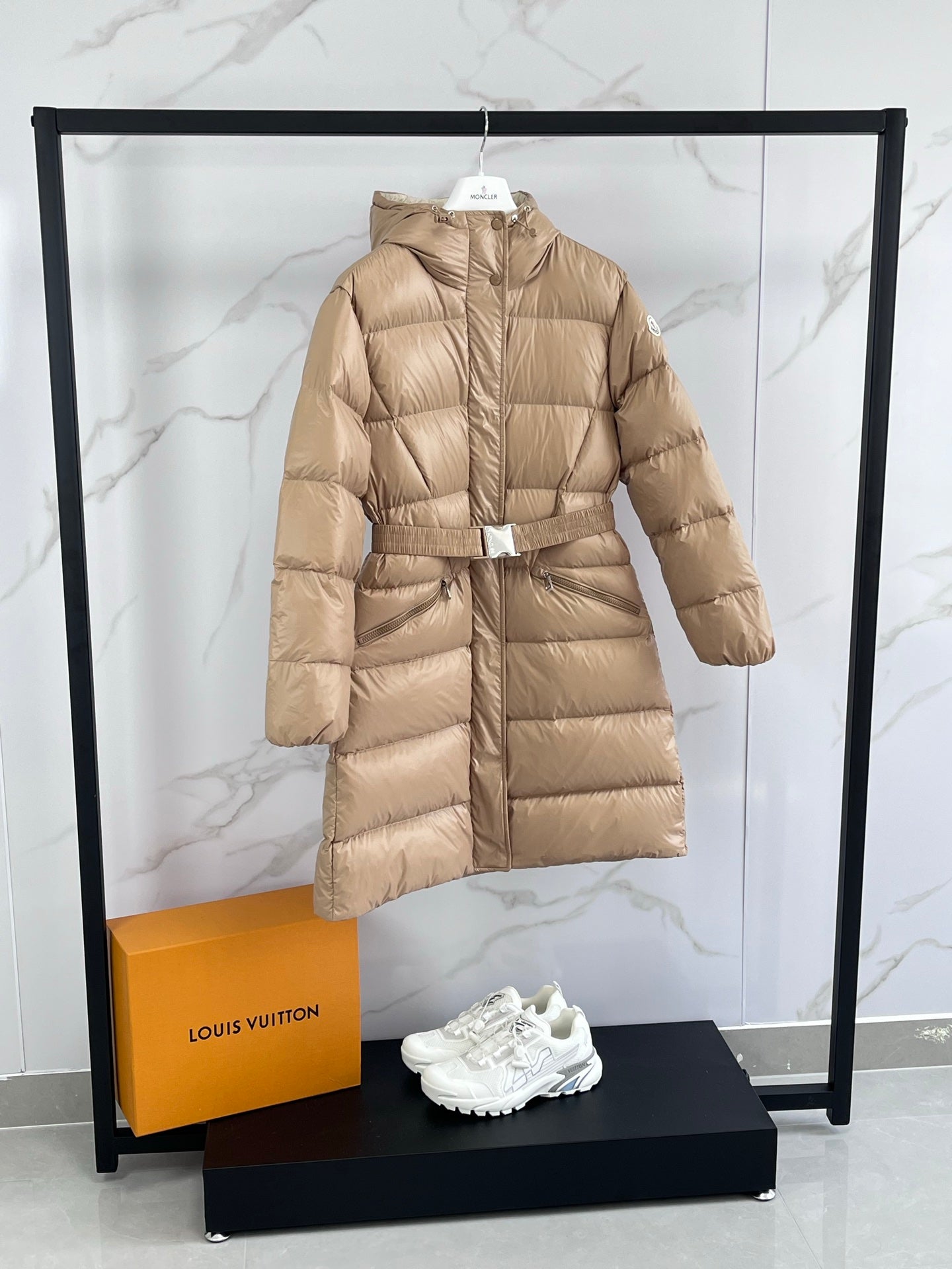 Tan long puffer coat with hood and front zip, cinched waist belt
