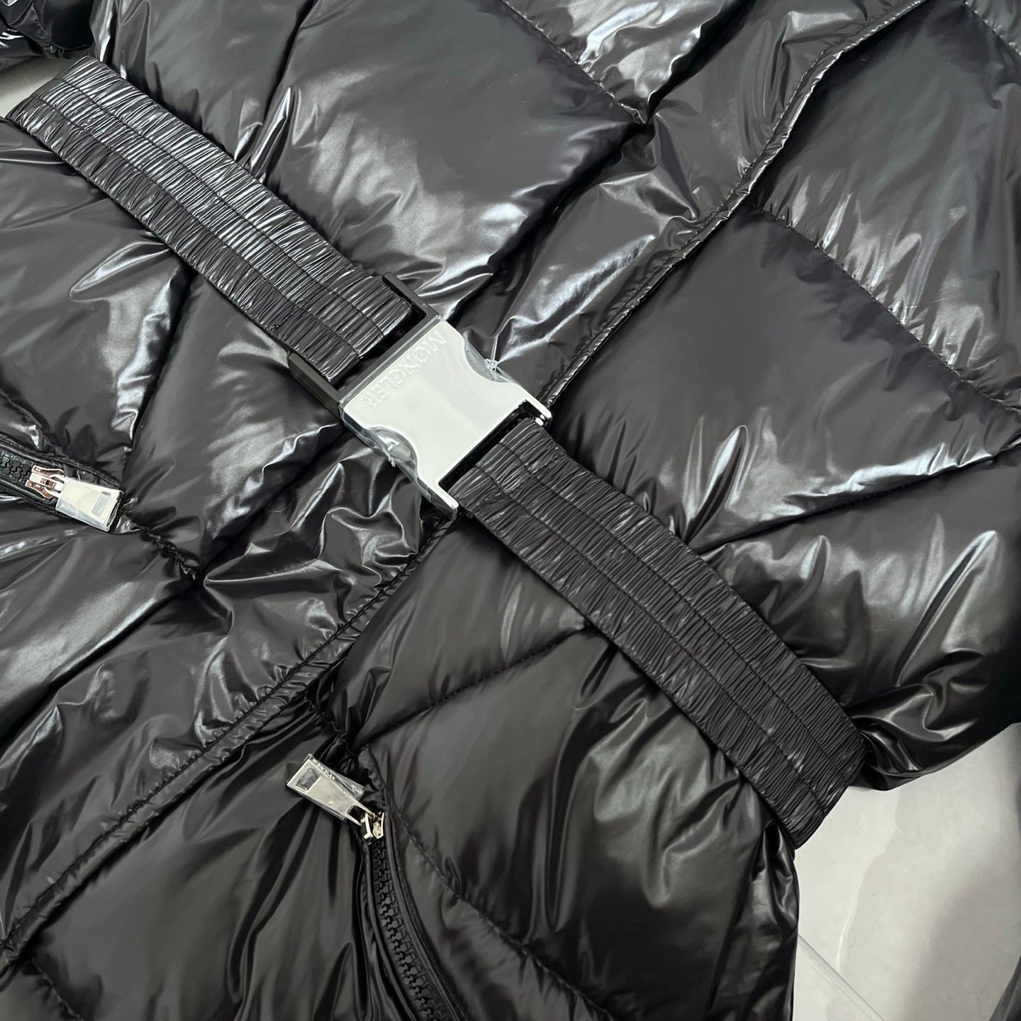 Front zipper and ribbed strap with snap tabs on dark gray puffer jacket