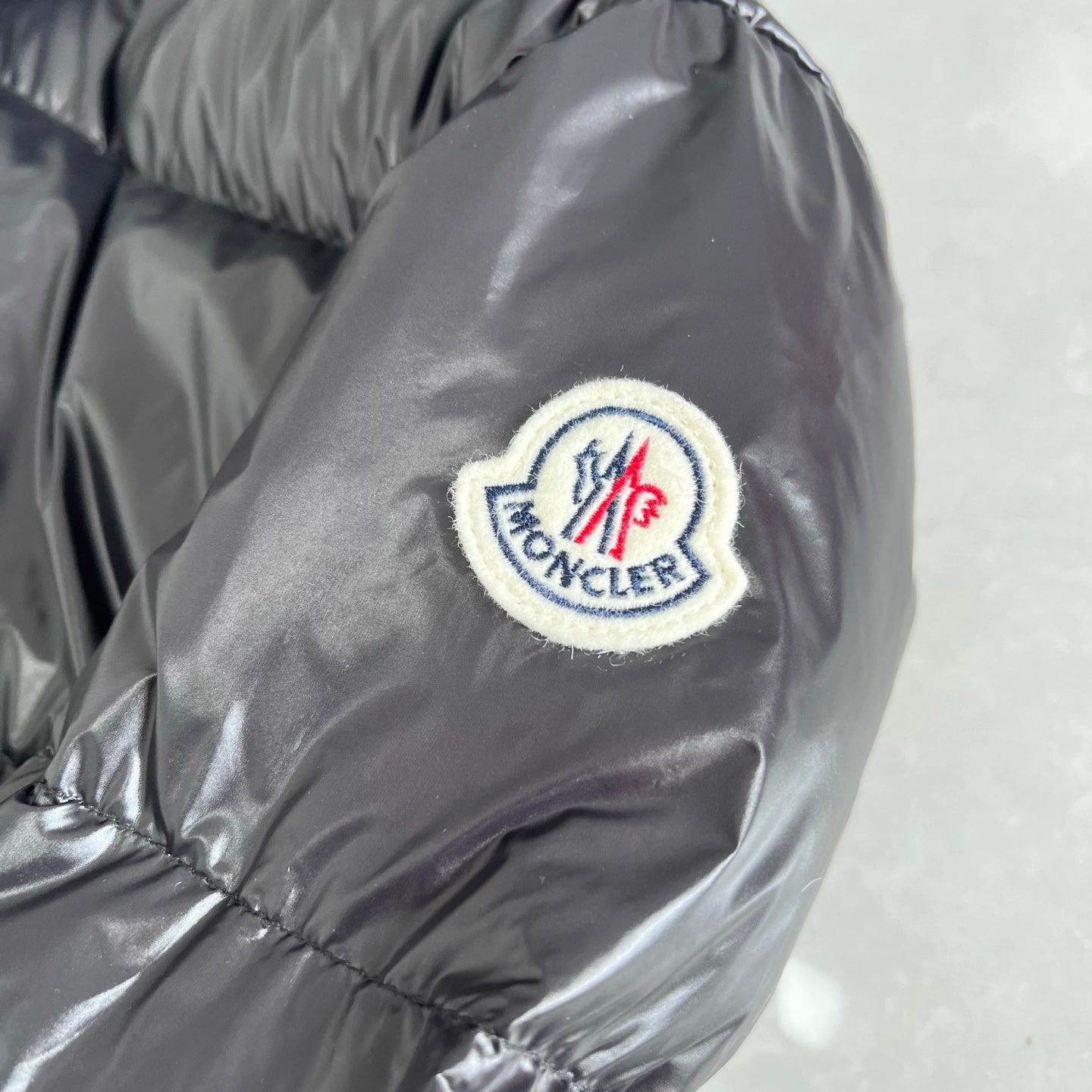 Moncler logo patch on dark gray puffer jacket sleeve