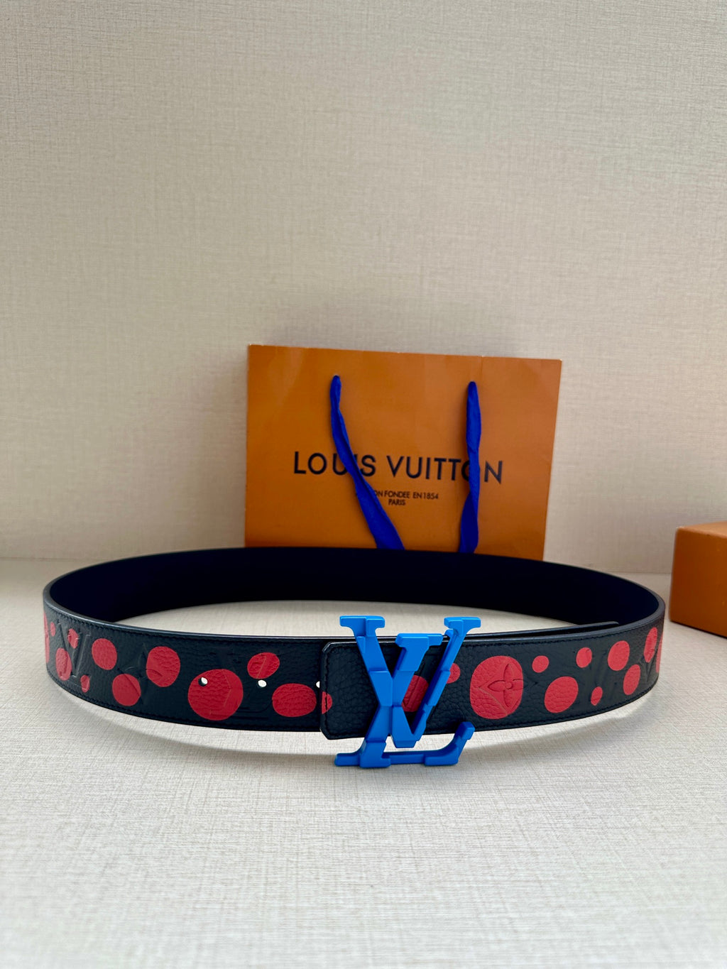Dark navy belt with red dot pattern and blue LV buckle
