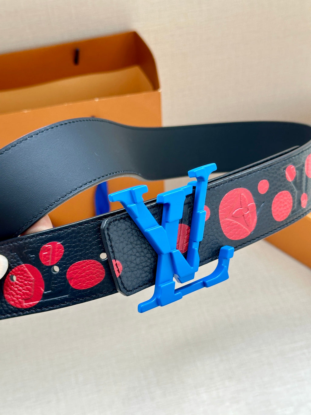 Dark navy leather belt with red circular print and large blue LV buckle detail