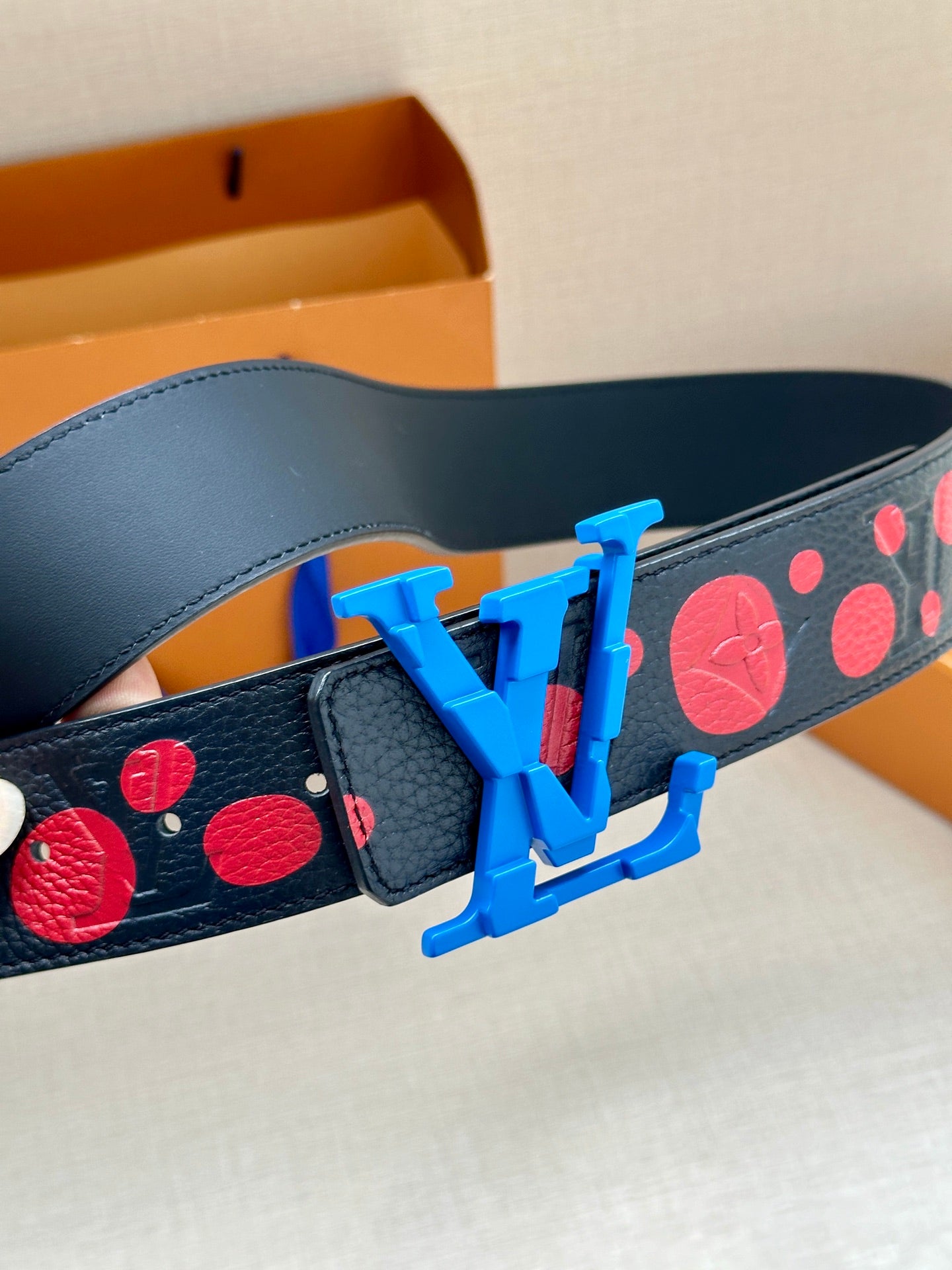 Dark navy leather belt with red circular print and large blue LV buckle detail