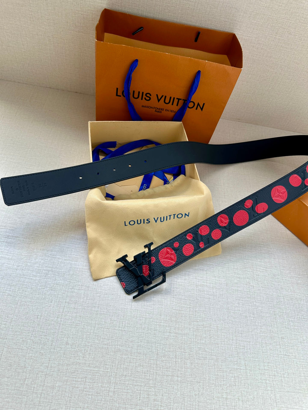 Louis Vuitton belt laid flat, dark blue with red circle motif and silver V buckle