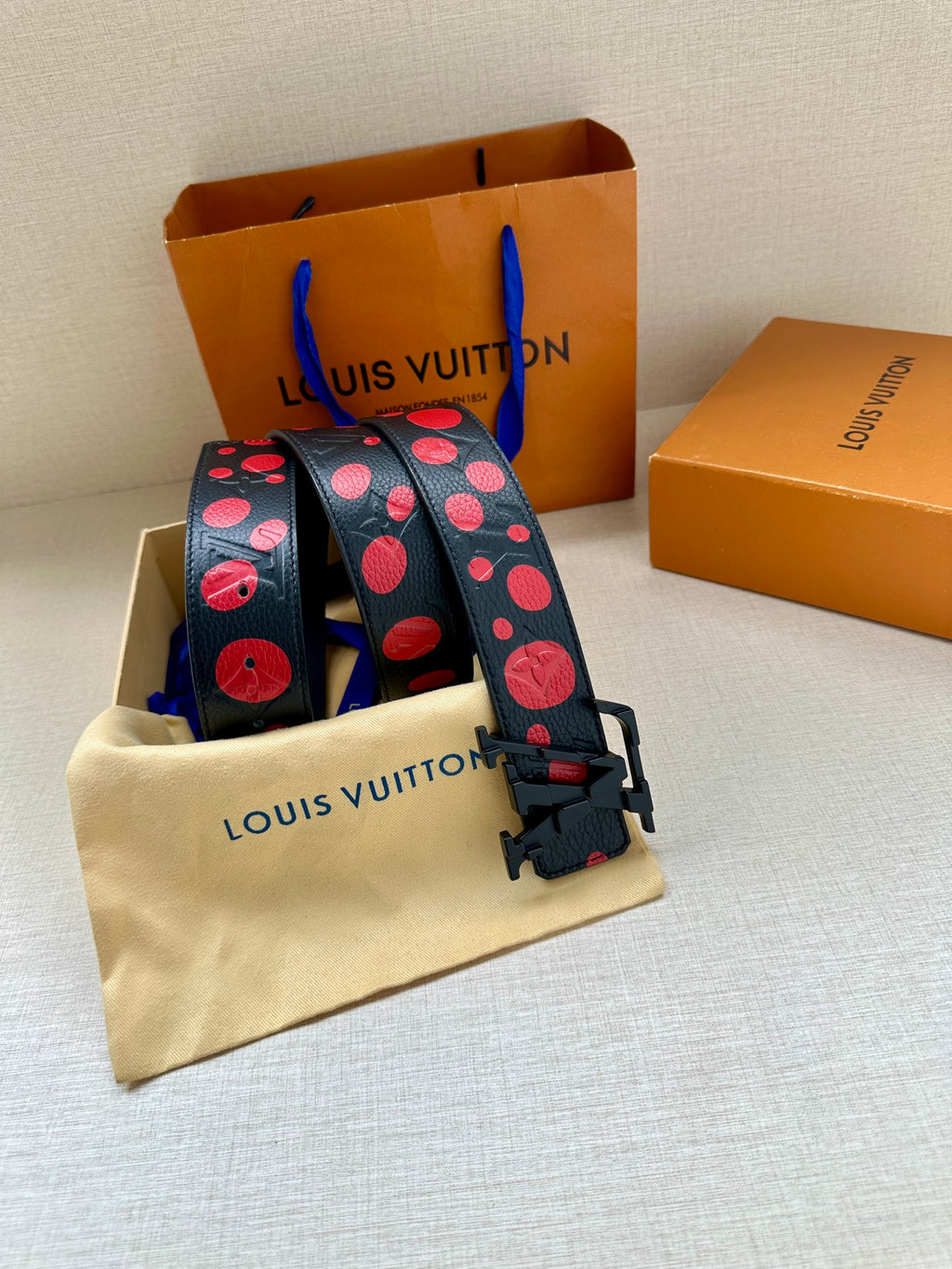 Louis Vuitton belt with red circle print on dark blue strap and adjustable buckle