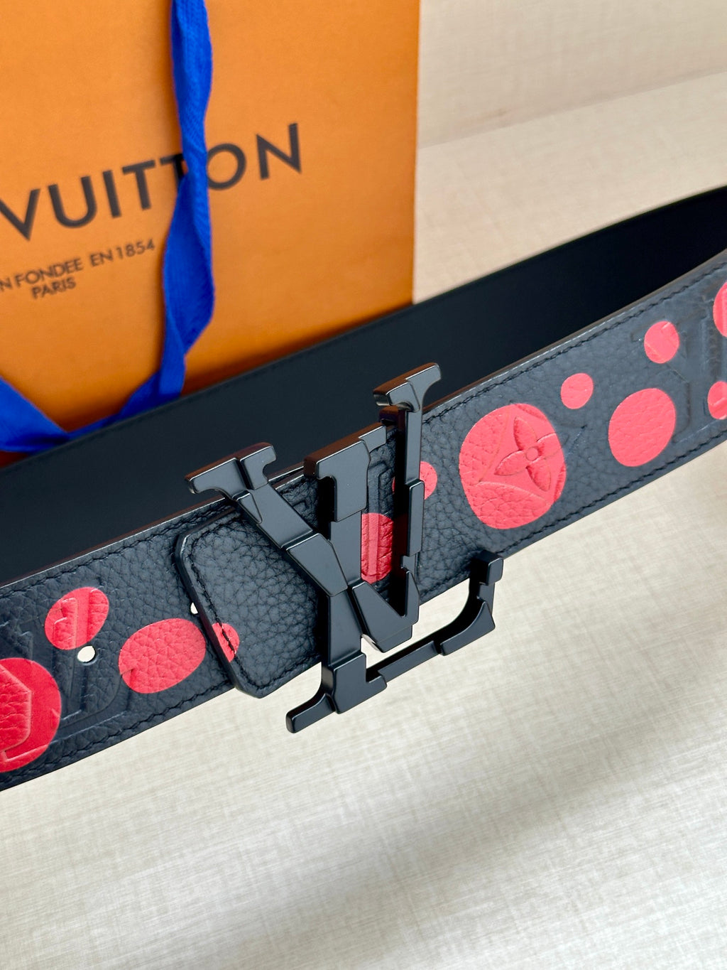 Louis Vuitton belt buckle detail on dark blue strap with red circle pattern