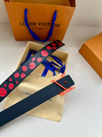 Navy belt with red dot pattern and orange LV buckle, shown in open box