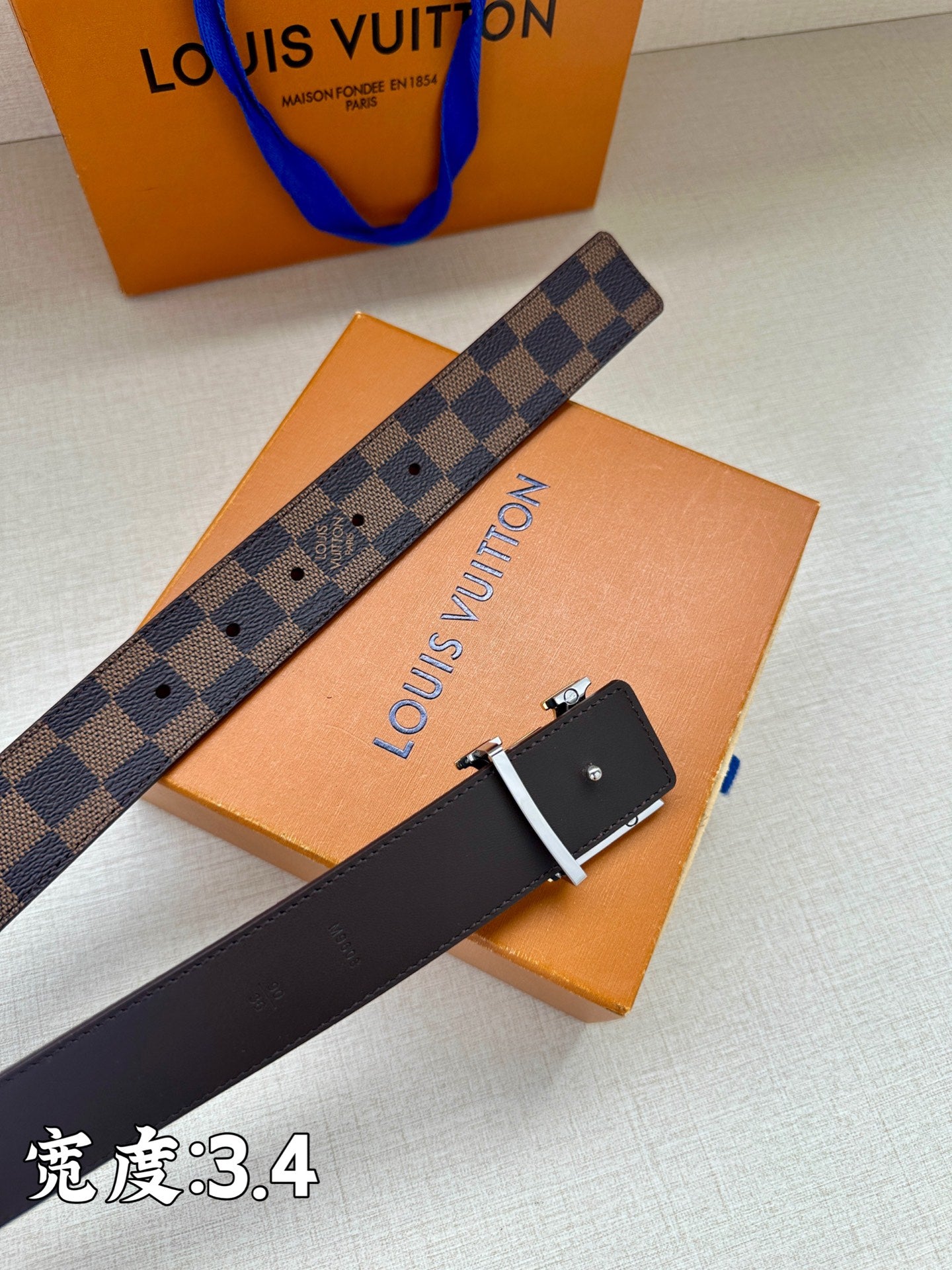 Checkered leather belt with LV logo buckle on flat surface