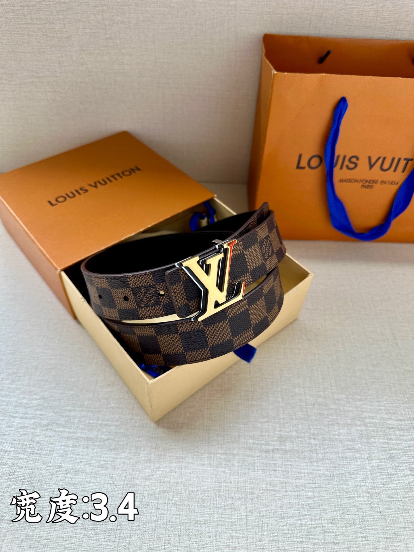Checkered leather belt with LV logo buckle resting in gift box