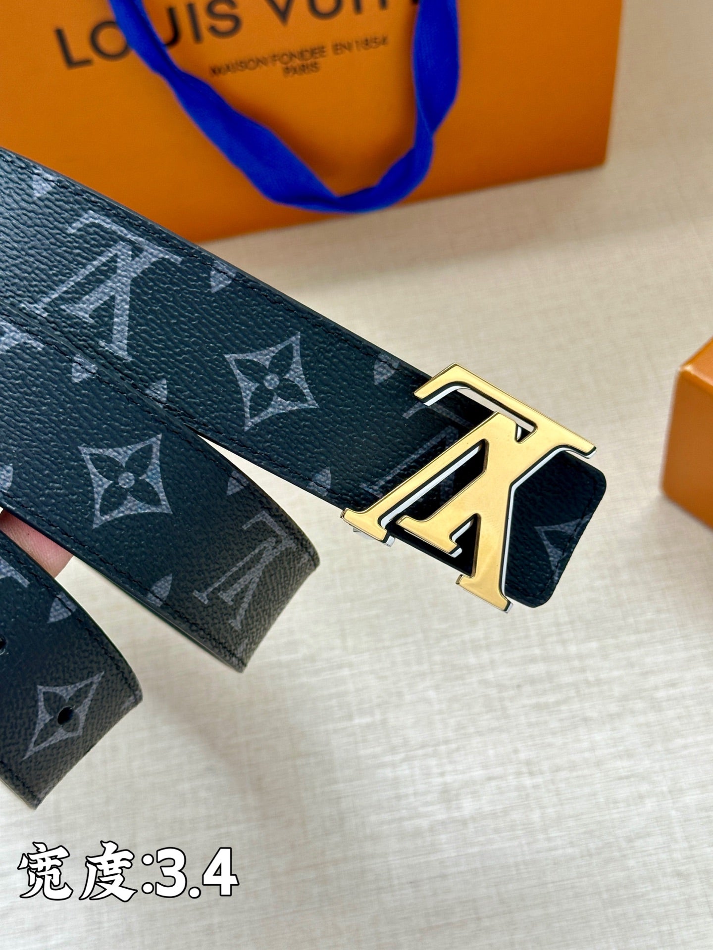 Louis Vuitton belt close-up showing dark blue monogram strap and gold buckle