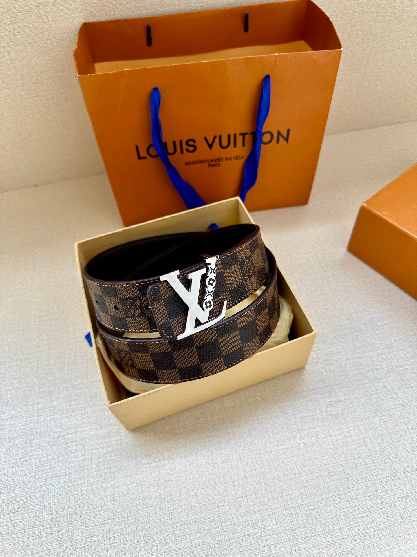 Louis Vuitton belt in box with dark check strap and gold LV buckle, black leather backing