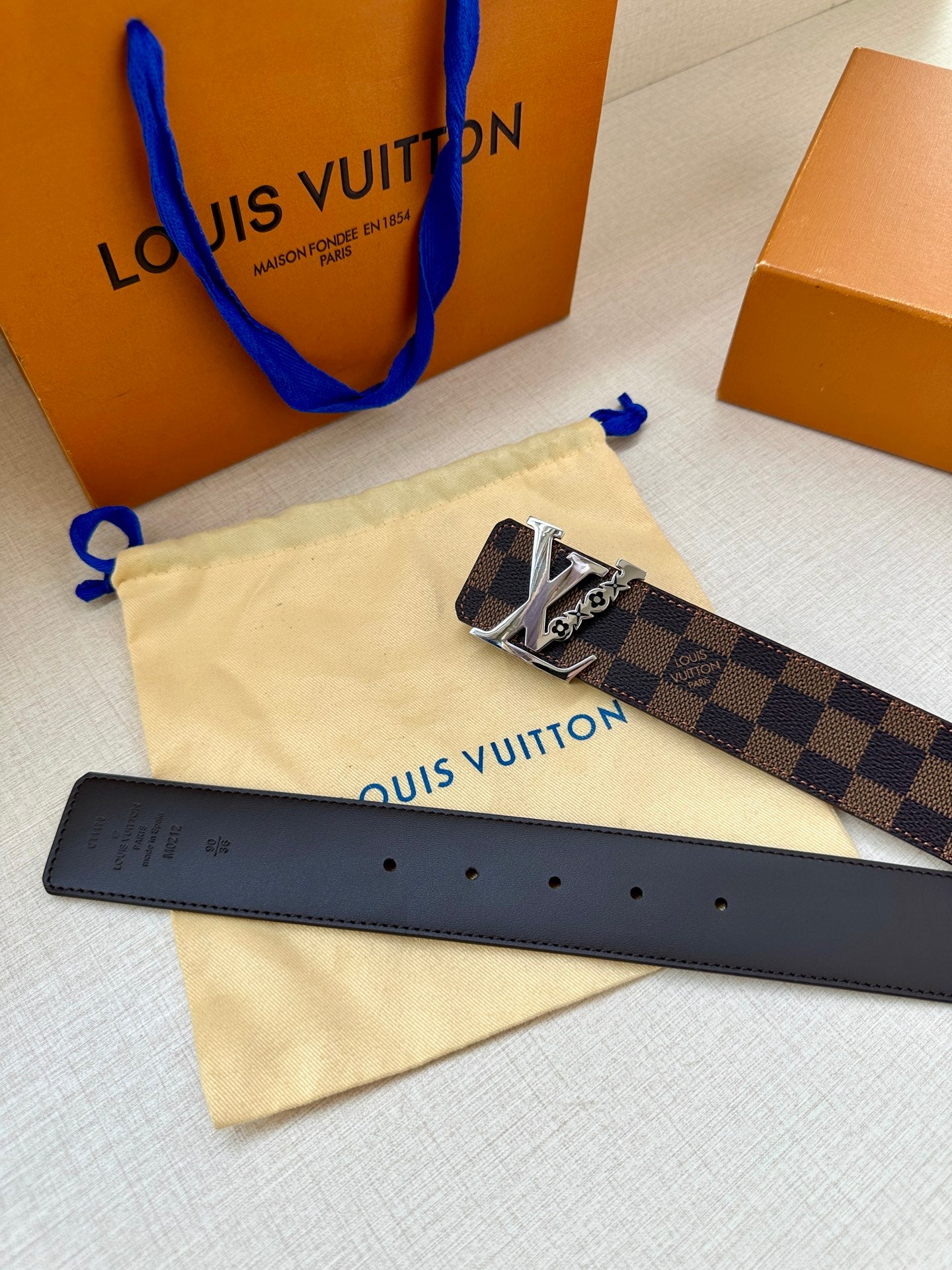 Louis Vuitton belt with dark check canvas strap, gold LV buckle, and black leather underside