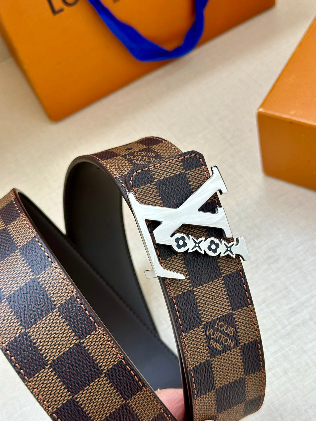 Louis Vuitton belt side view: dark check canvas with gold buckle and inner black lining