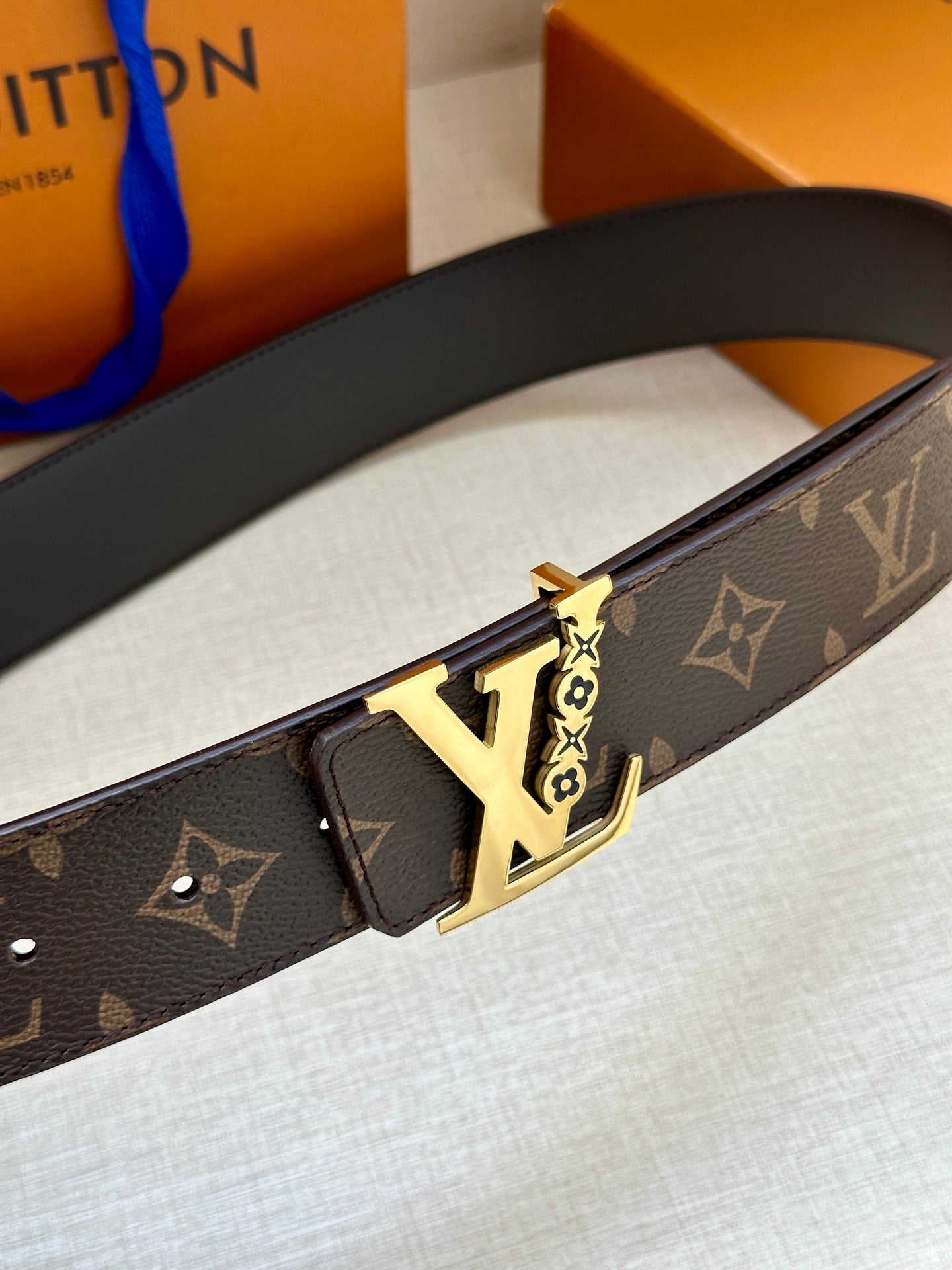 Louis Vuitton belt close-up with gold buckle and dark brown monogram strap