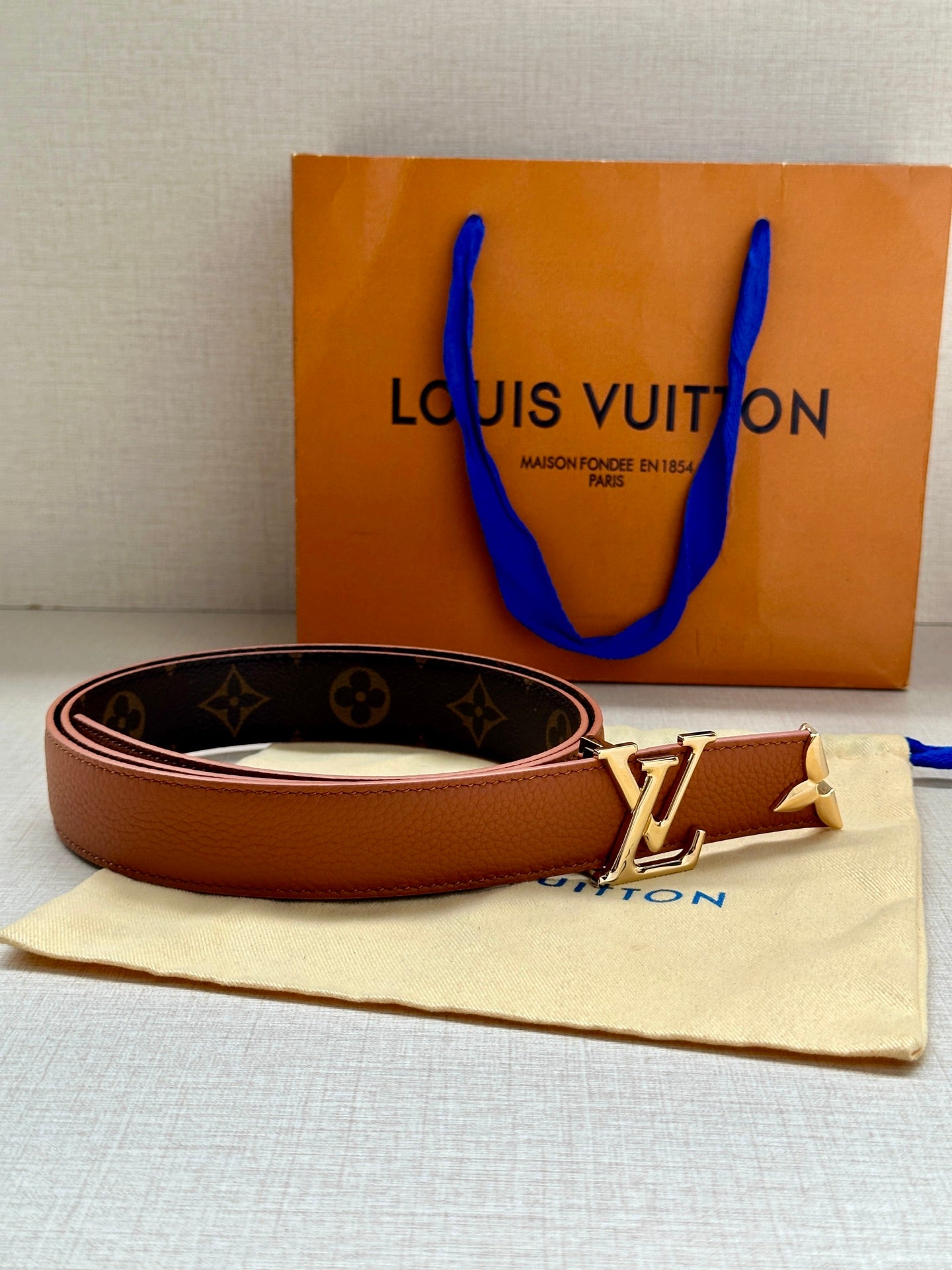 Louis Vuitton belt with tan leather reverse, brown monogram strap, and gold buckle
