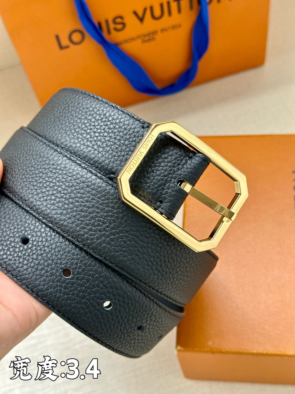 Louis Vuitton leather belt close-up, dark blue with gold-tone buckle and side slots