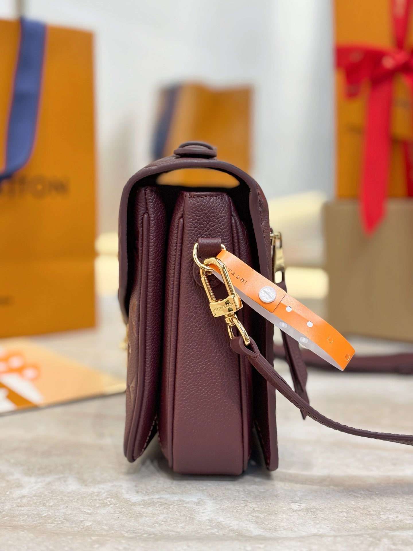 Louis Vuitton mini flap shoulder bag standing, dark plum, gold strap hardware and handle.