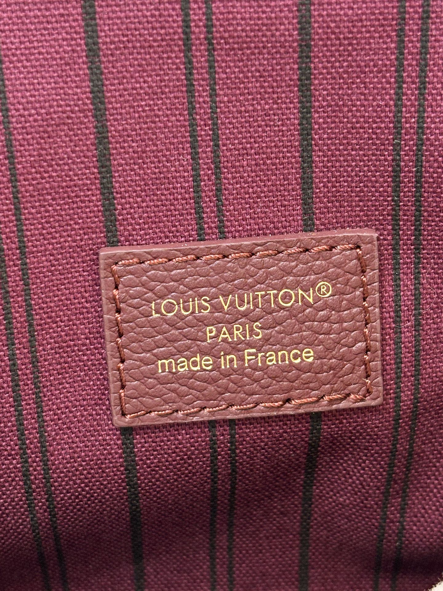 Louis Vuitton mini flap shoulder bag label, dark plum fabric with brand text.