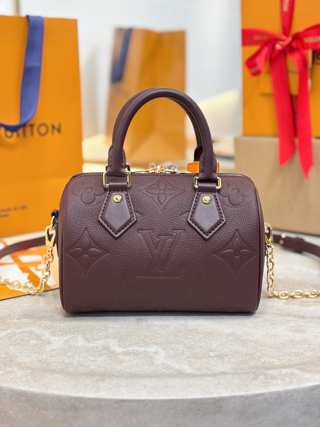 Louis Vuitton maroon leather handbag with structured top, dual handles, gold-tone accents