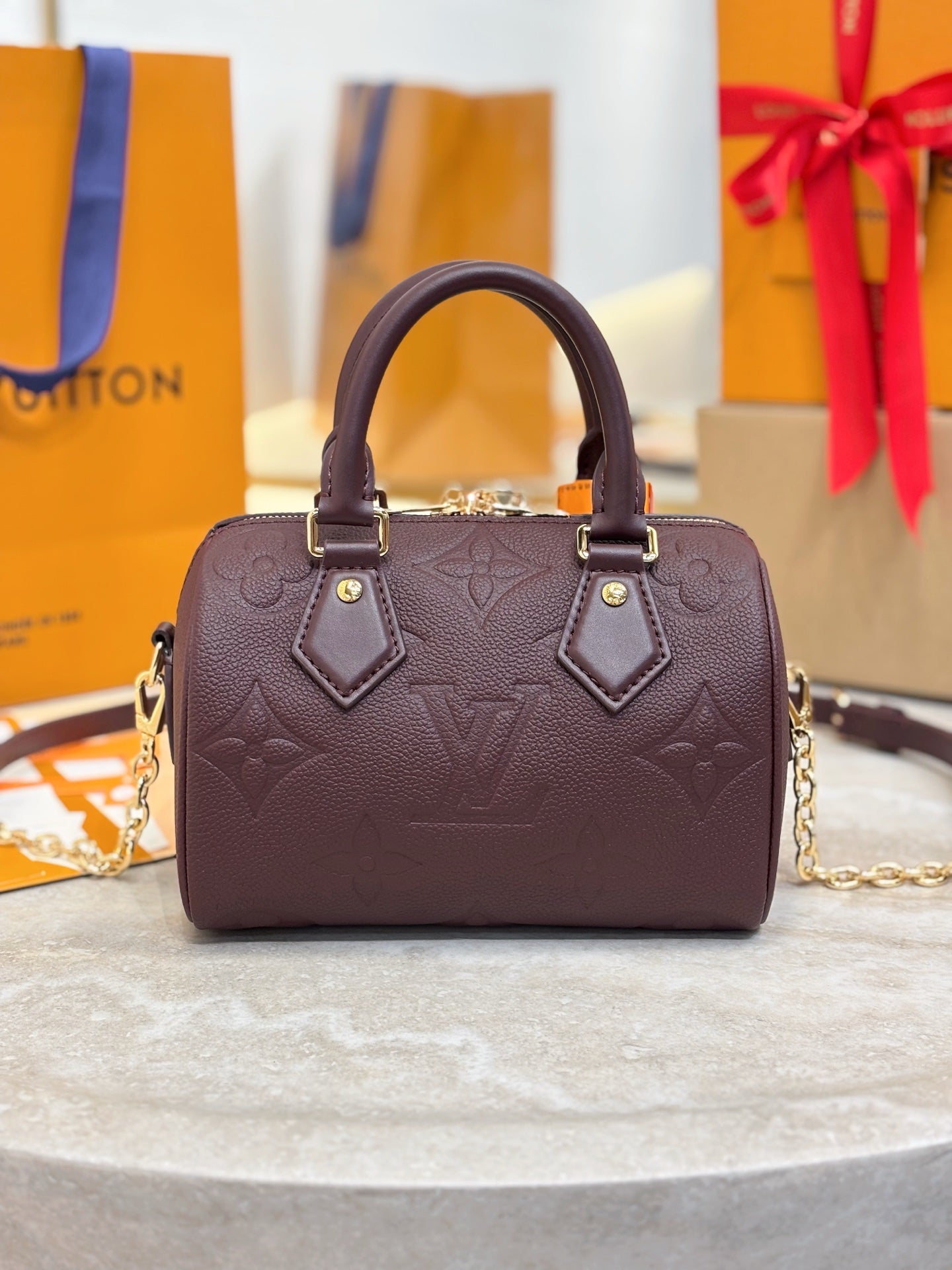 Louis Vuitton maroon leather handbag with structured top, dual handles, gold-tone accents