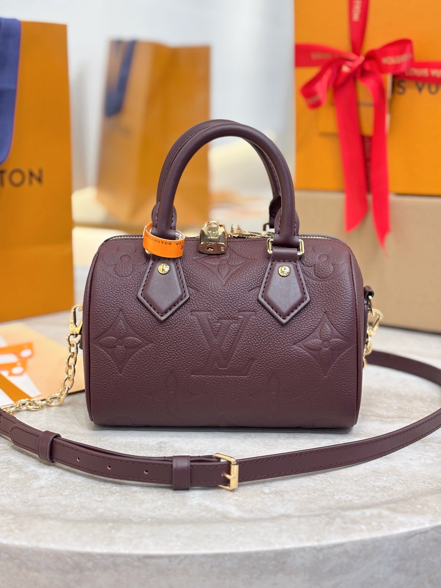 Louis Vuitton maroon leather handbag with top handles and gold-tone hardware, chain strap