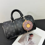 Small donut key pouch attached to a black monogram duffel bag
