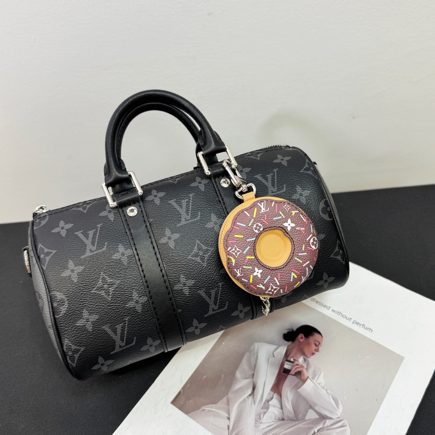 Small donut key pouch attached to a black monogram duffel bag
