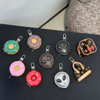 Assorted small keychains in dark tones, including donut and heart shapes, metal clips