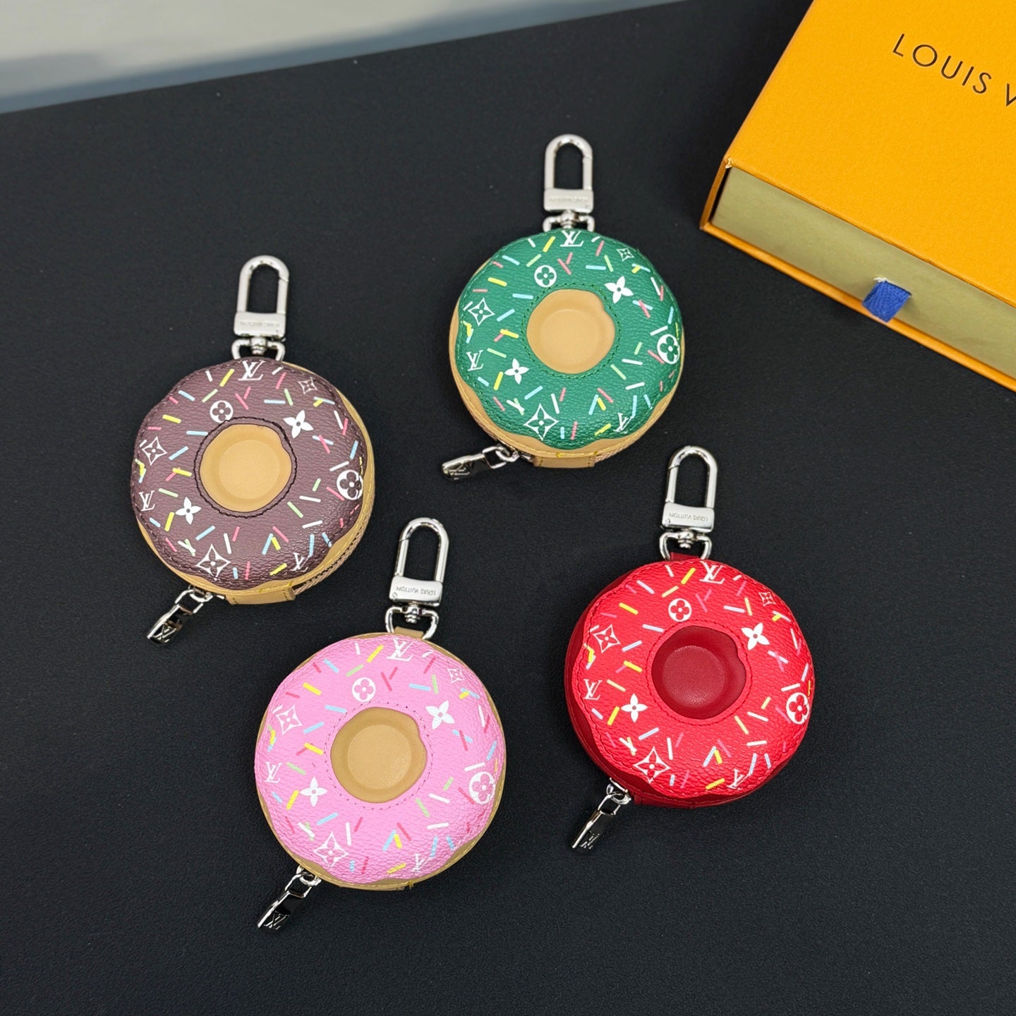 Donut-shaped keychain with green monogram print, gold center, metal clip