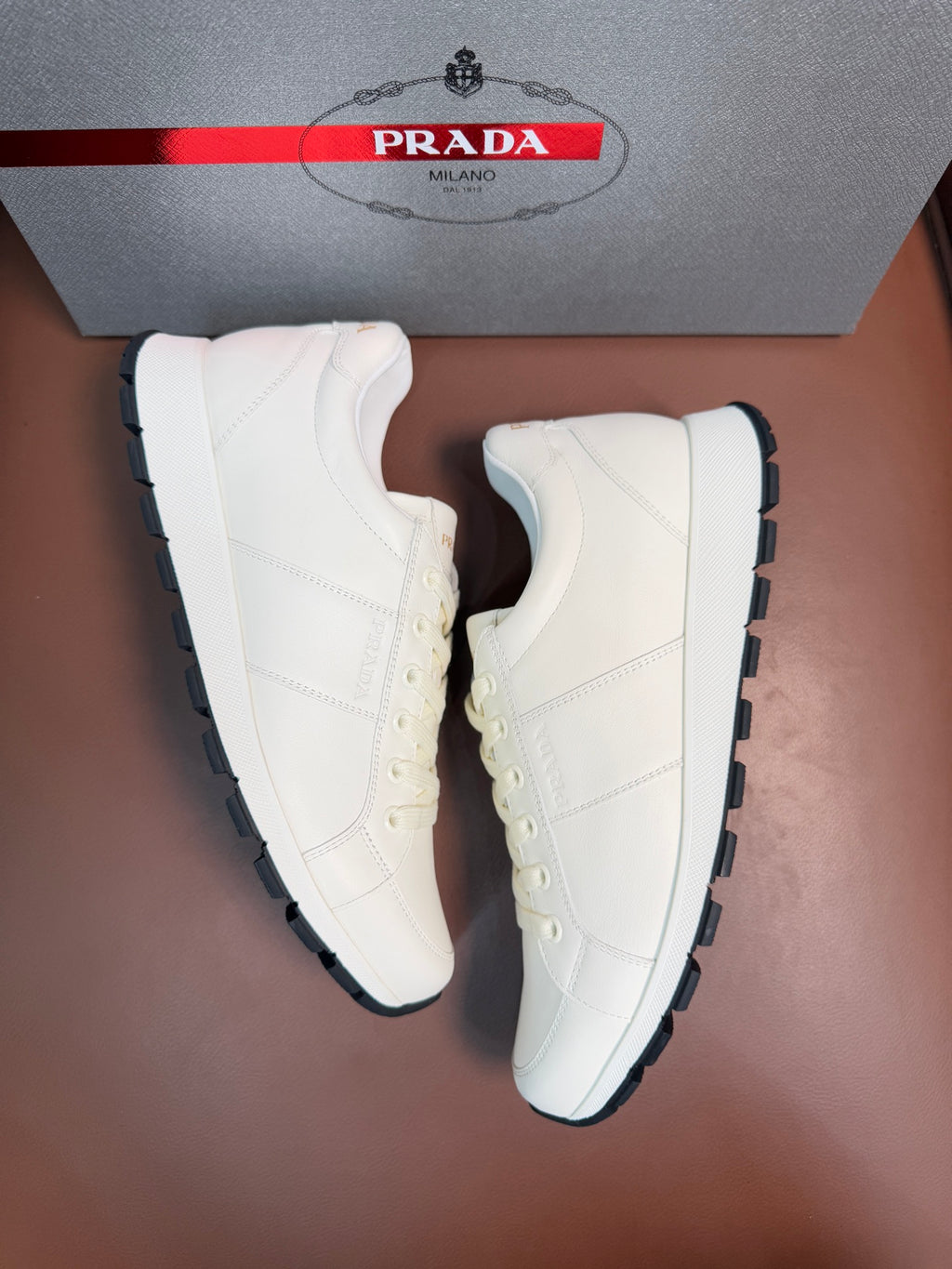 White lace-up low-top sneakers with black-edged rubber outsole