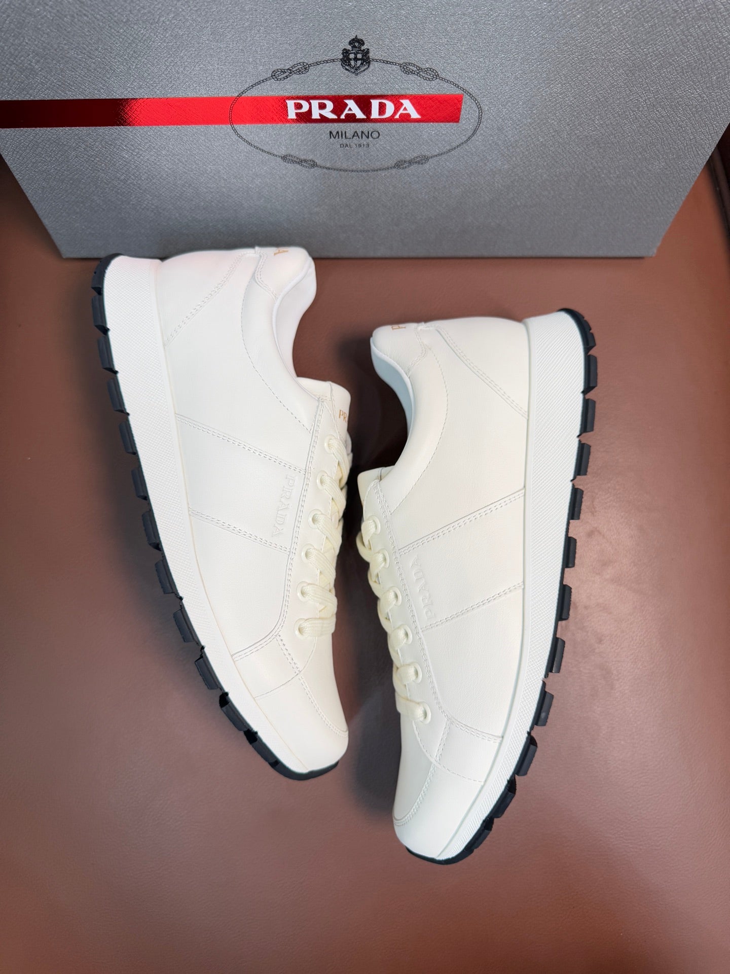 White lace-up low-top sneakers with black-edged rubber outsole
