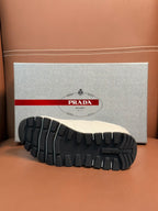 White sneaker outsole view with thick tread and Prada branding on sole
