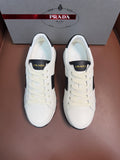 Pair of white Prada unisex sneakers with black side panels and lace-up design