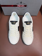 Pair of white Prada unisex sneakers with black side panels and lace-up design
